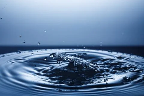 Drop of water falling down in the water Stockfoto's