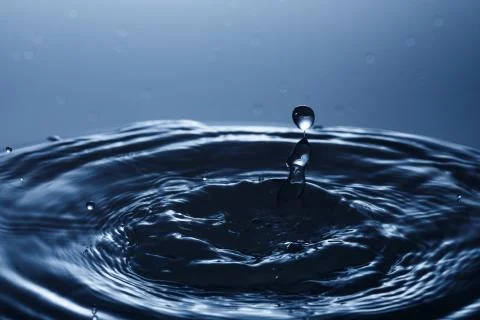 Drop of water falling down in the water 스톡 사진