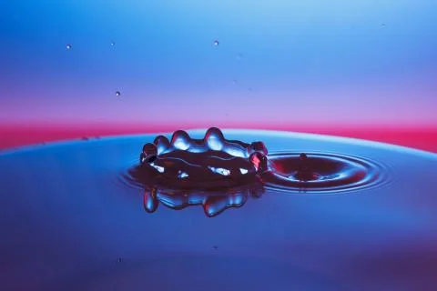 Drop of water falling down in the water Stock Photos