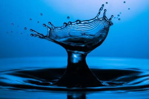 Drop of water falling down in the water Stock Photos