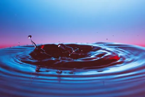 Drop of water falling down in the water 写真素材