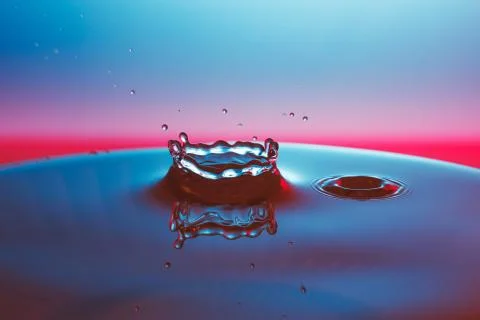 Drop of water falling down in the water Stock Photos