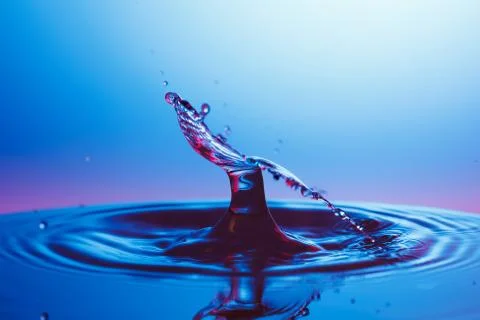 Drop of water falling down in the water Stock Photos