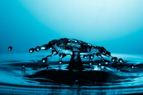 Drop of water falling down in the water 库存照片