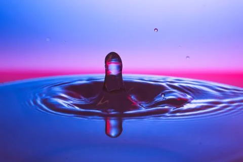 Drop of water falling down in the water Stock Photos