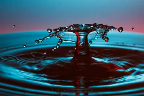 Drop of water falling down in the water Stock Photos