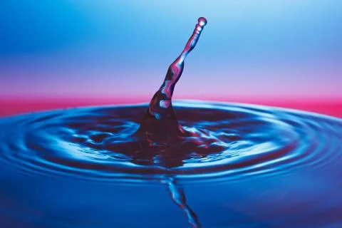 Drop of water falling down in the water 写真素材