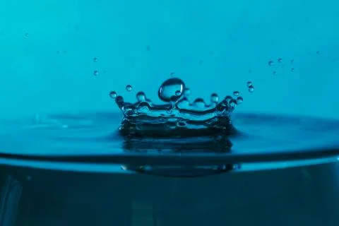 Drop of water falling down in the water Stock Photos