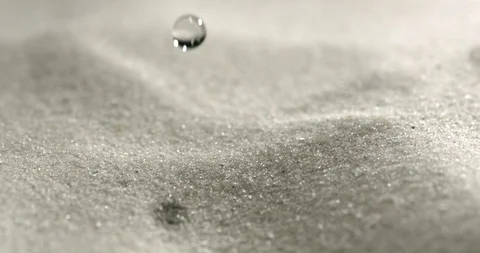 A drop of water is falling in slow motion on the sand. Vidéo 115417198