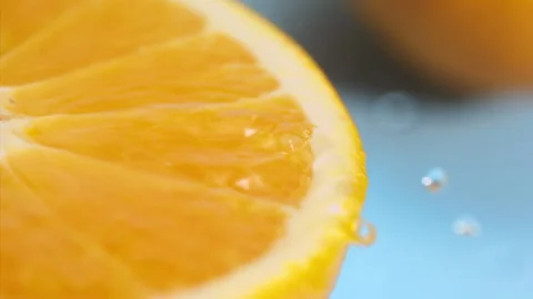 A drop of water falls on a slice of orange on the blue background at super slow  Stock Footage 338064167