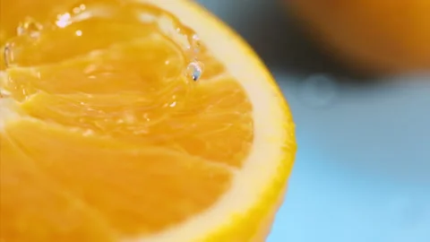 A drop of water falls on a slice of orange on the blue background at super slow  Stock Footage 338064239