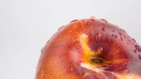 A drop of water flows down a fresh juicy peach. Fresh organic Peach covered w Stock Photos