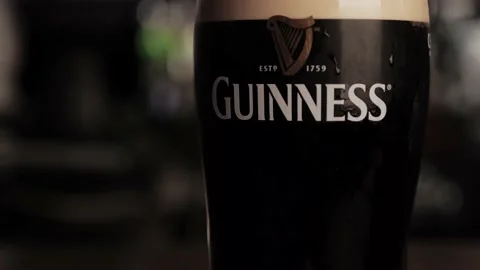 A drop of water flows down a glass with cold dark Guinness bee Stock Footage 138190546