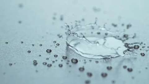 A drop of water hits a surface and shatters into small droplets. Vídeo Stock 84075771