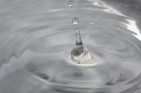 Drop of water splashed creates waves. Stock Photos