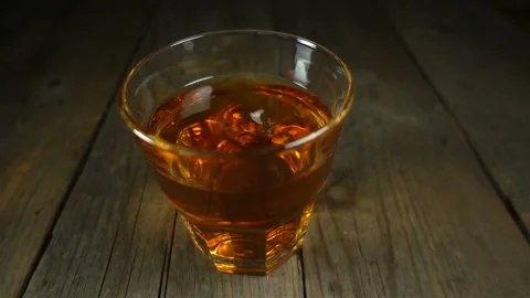 A drop of whiskey in slow motion falls in a filled glass Stock Footage 131016766