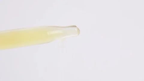 Drop of yellow serum falling down out of glass pipette, close up. Drops of .. Stock Footage 262417329