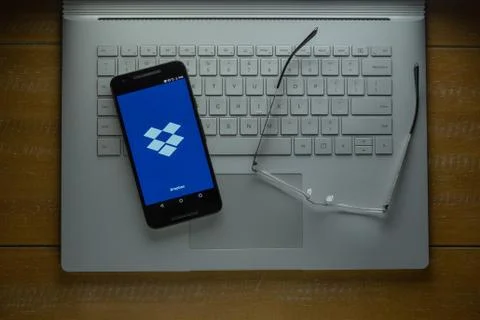 Dropbox app loading on Android phone in a dark room Stock Photos