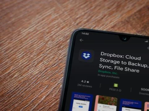 Dropbox app play store page on the display of a black mobile smartphone on wo Stock Photos