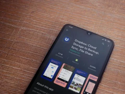 Dropbox app play store page on the display of a black mobile smartphone on wo Stock Photos