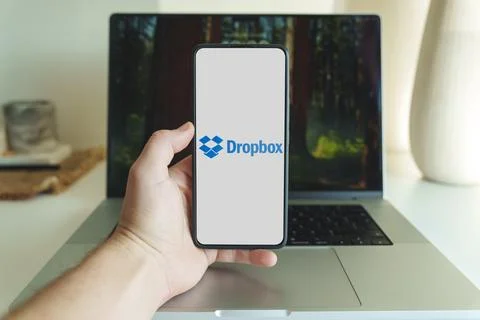 DropBox cloud storage application logo on smartphone screen in front of laptop Stock Photos