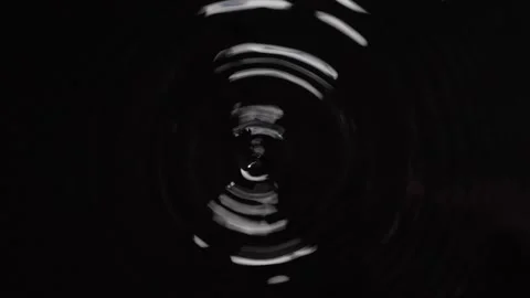 Droplet dropping on a surface of a water isolated on black background Stock Footage 247107610