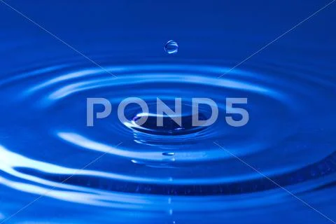 Droplet falling in the blue water Stock Photos