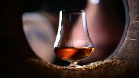 Droplets of bourbon whiskey elegantly flow down the sides of a glass Stock Footage 278616058