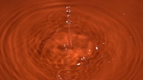 Droplets create ripples in orange liquid during fascinating close-up observation Stock Footage 322815402