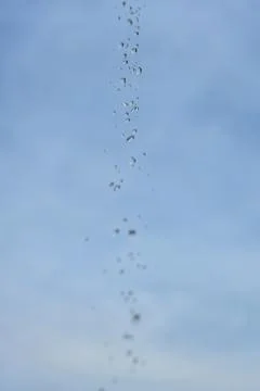 Droplets fall slowly against a clear blue sky Stock Photos
