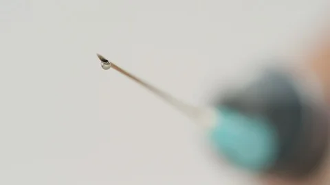 Droplets falling from a syringe needle Stock Footage 99750277
