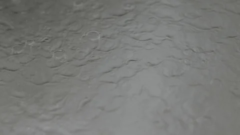 Droplets of rain falling on the surface creating ripples, running water Stock Footage 126142944