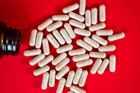 Dropper bottle with capsules on red surface. Concept of modern medicine Stock Photos