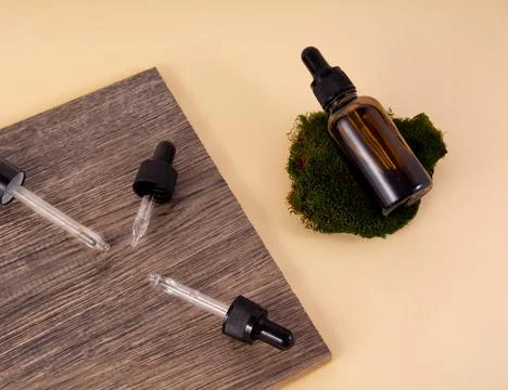 Dropper from a bottle of cosmetics on ceramic tiles. A bottle of serum lies o Stock Photos