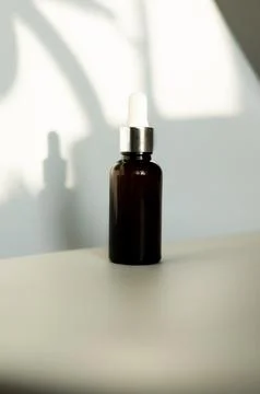 Dropper bottle without label on white background illuminated by sunlight Foto stock