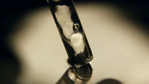 Dropper dipped into clean water at bright backlight Stock Footage 238932060