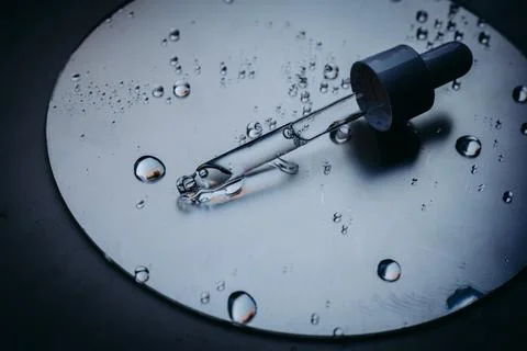 Dropper with serum on a reflective surface, representing beauty and skincare Stock Photos