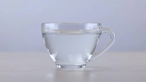Dropping and Stirring Sugar Cube in Glass Cup of Water Stock Footage 341927663