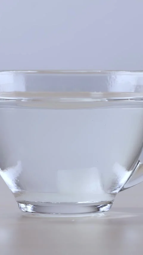 Dropping and Stirring Sugar Cube in Glass Cup of Water Видео 342698433