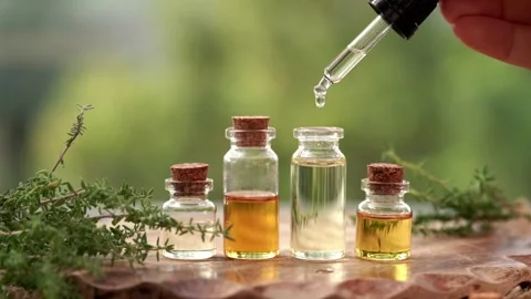 Dropping aromatherapy essential oil into a glass bottle, with fresh thyme plant Stock Footage 329187742