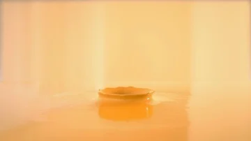Dropping ball in orange juice or paint making beautiful crown splash Stock Footage 85930699