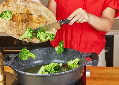 Dropping broccoli florets into pan Stock Photos