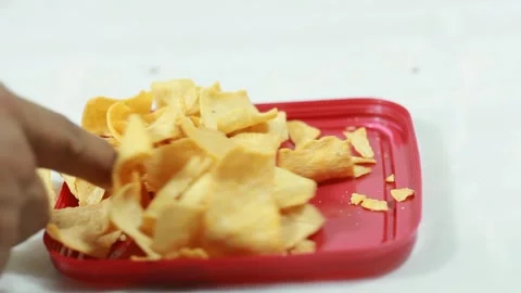Dropping chips into a red plate with a white background Stock Footage 297405913