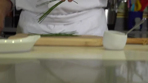 Dropping chives on chopping board before finely chopping, close up 库存影片 138109428