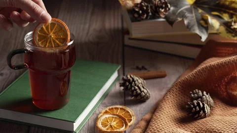 Dropping a dried orange slice into a glass of hot tea, cozy autumn and winter Stock Footage 343888336