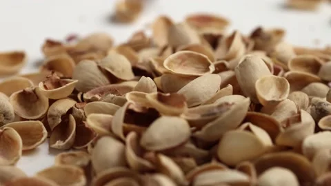 Dropping empty pistachios shells on white background Stock Footage 228690911