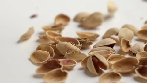 Dropping empty pistachios shells on white background Stock Footage 228691505