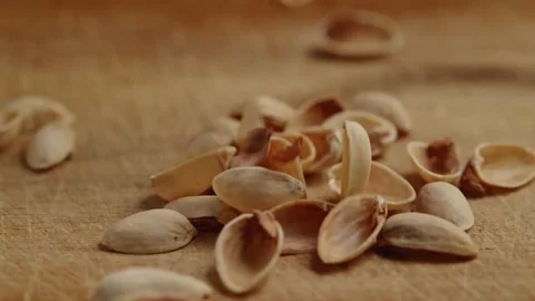 Dropping empty pistachios shells on wooden cutting board Stock Footage 228690303