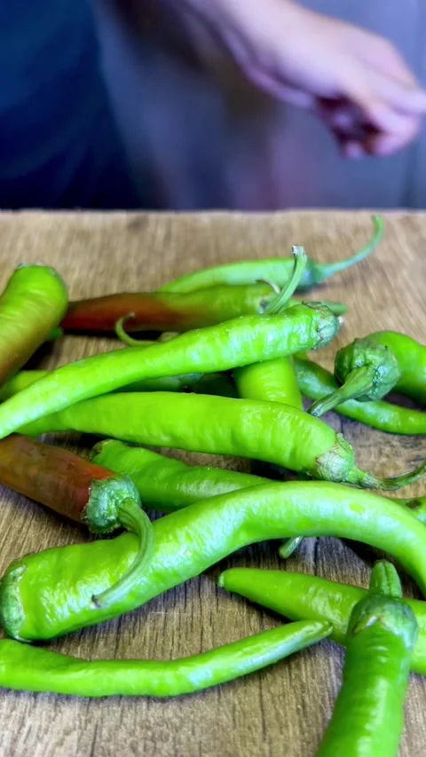Dropping green chilli on a chopping board for cutting. Stock Footage 287435681