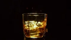 Ice cube falling into whisky glass – License Images – 11039807